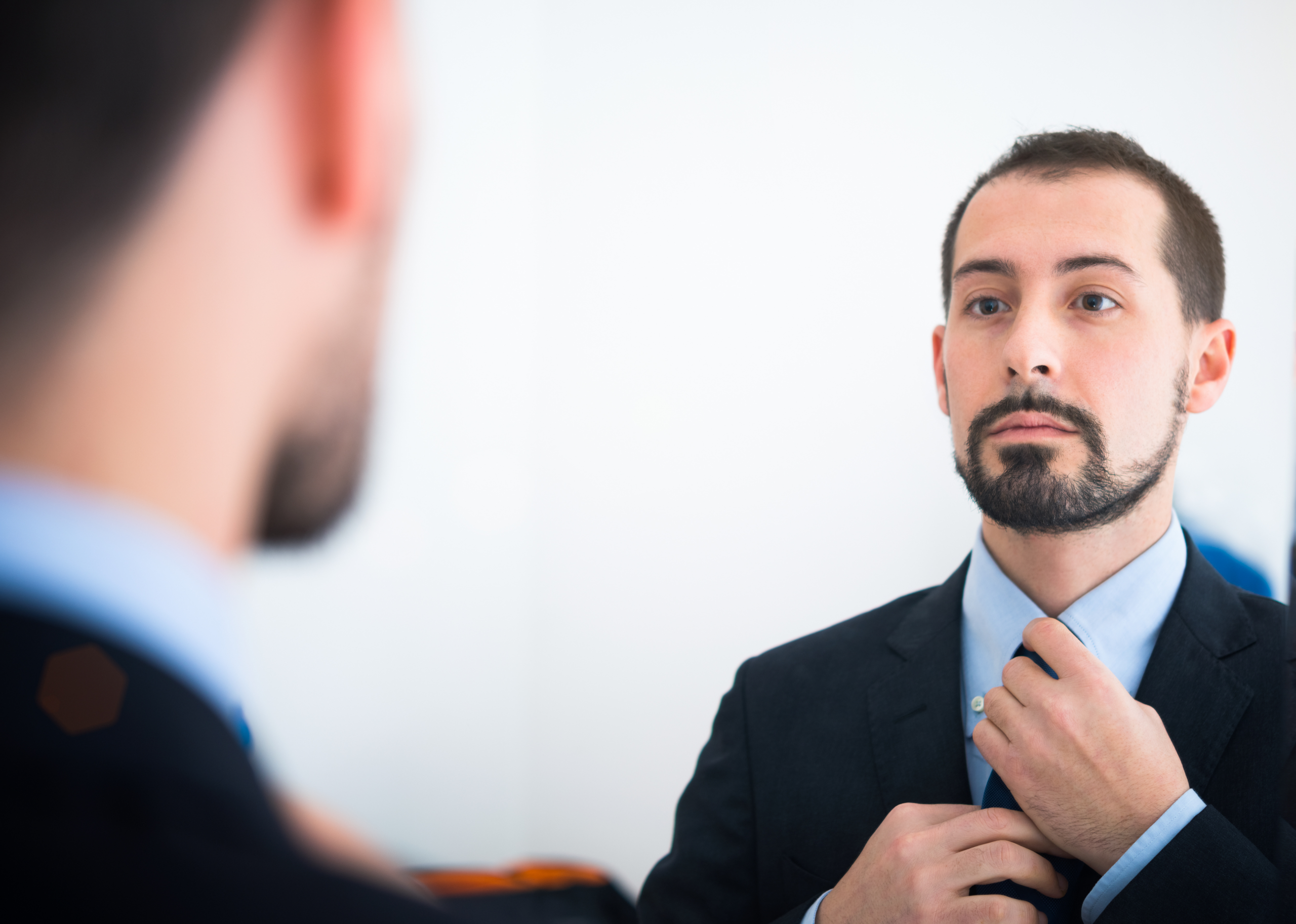 Persoon kijkt kritisch in een spiegel als metafoor voor perfectionisme en spreekangst