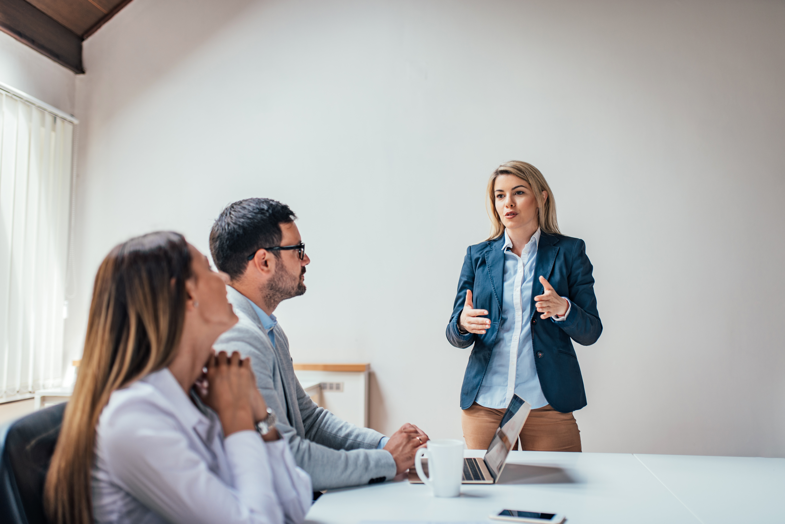 Persoon met trillende stem tijdens presenteren staat kalm voor een groep collega's in een vergaderruimte