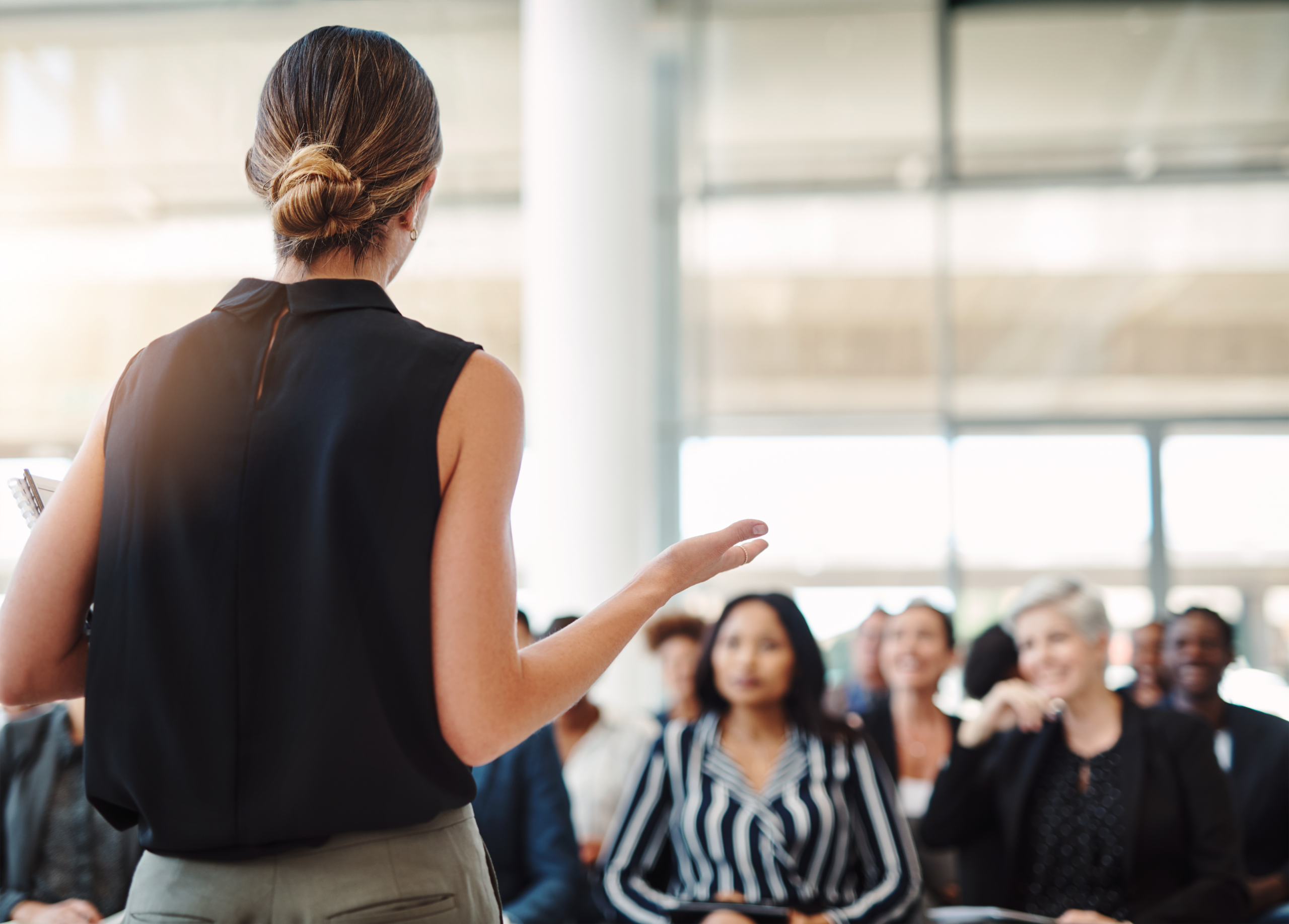 Vrouw die spreekangst overwint door zelfverzekerd te spreken voor collega's in een professionele omgeving